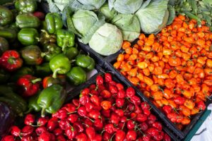 A vibrant display of fresh vegetables including peppers and cabbage at an outdoor market.